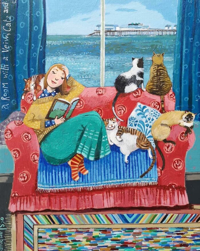 Woman reading on a couch surrounded by five cats with ocean view, colorful cat-themed artwork in cozy room setting.