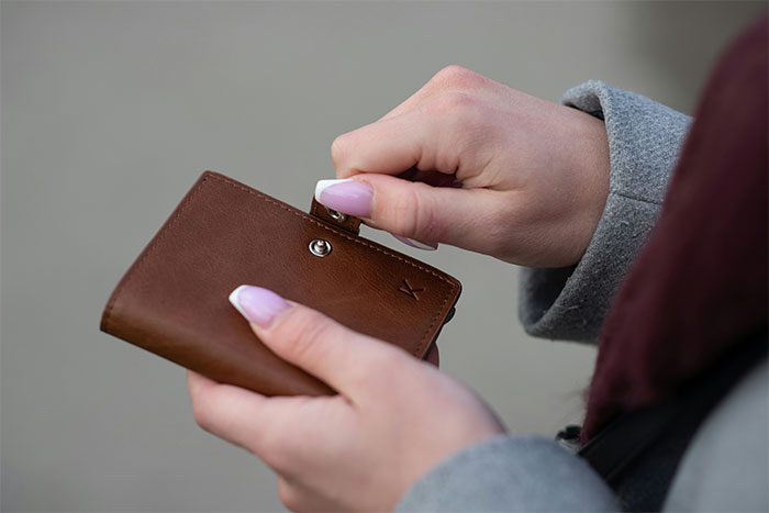 Woman holding a brown leather wallet revealing a secret, symbolizing the woman marries husband and exposes his big secret.