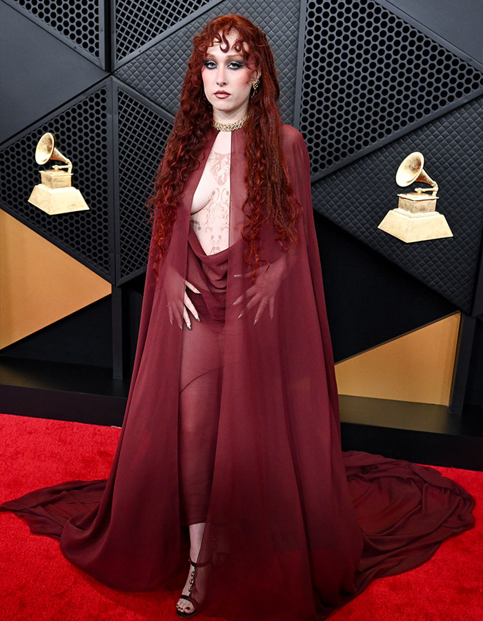 Chappell Roan wearing a sheer maroon dress and cape on the Grammys 2026 red carpet with a bold look analyzed by body language expert.