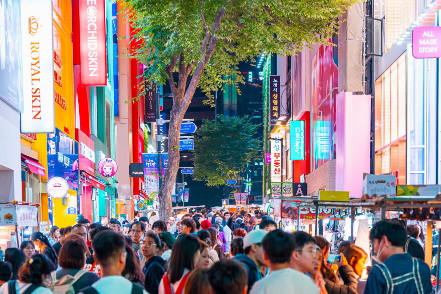 Busy city street in a vibrant nightlife scene with crowds and bright neon signs, showcasing cities where sleep is optional