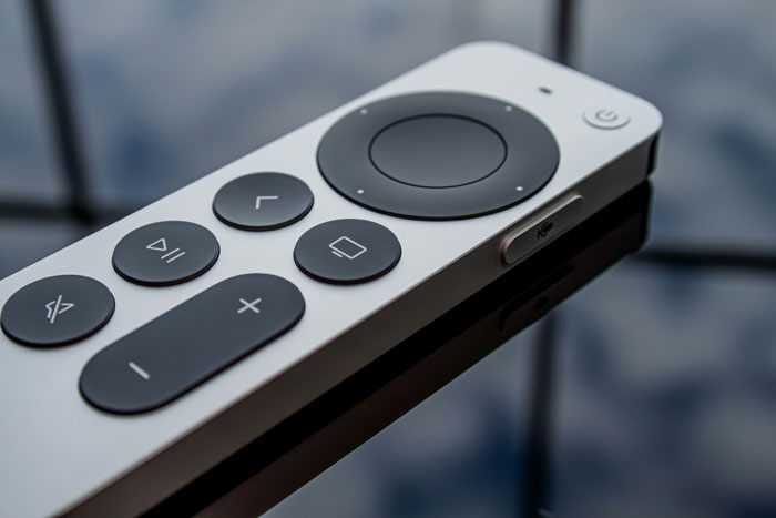 Close-up of a sleek remote control resting on a reflective surface, illustrating quick fixes that turned out genius.