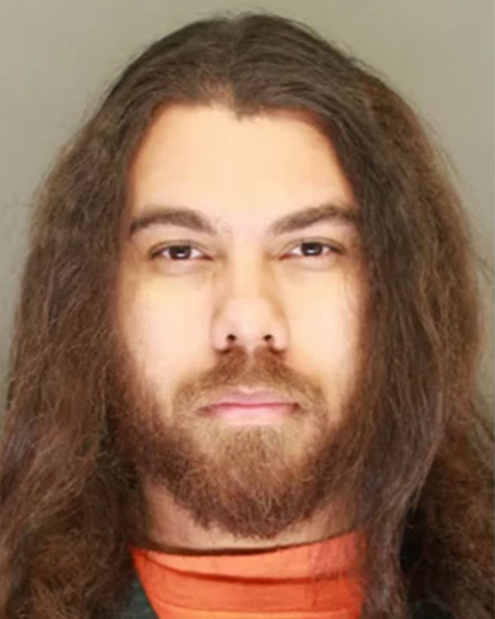Man with long hair and beard in an orange jumpsuit, related to missing woman 24 located after final call plea.