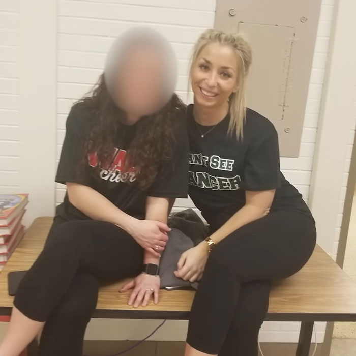 Two women sitting on a table in casual clothes, related to judge firing back at teacher after devastating student outcome.