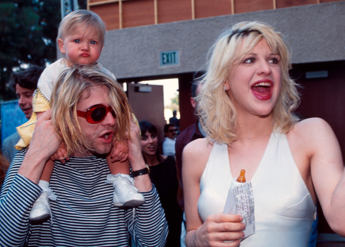 Courtney Love with Kurt Cobain and child outdoors, capturing a candid moment amid homicide claim discussions.
