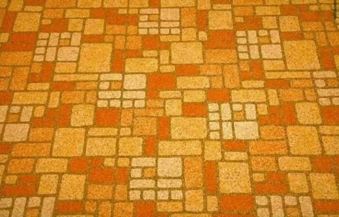 Retro orange and beige patterned carpet with geometric shapes, evoking nostalgic 70s and 80s interior design style.