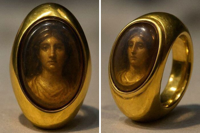 Golden museum artifact ring with a detailed engraved portrait of a woman from historical times on display