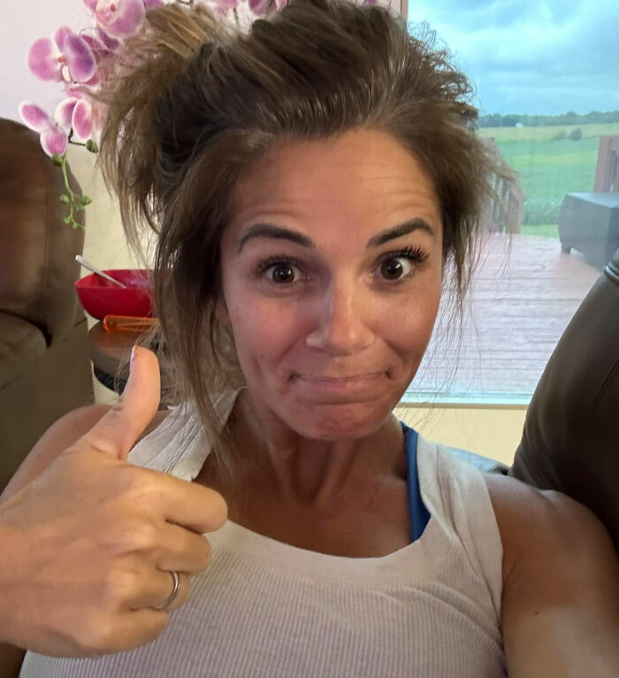 Woman giving thumbs up indoors with casual hairdo, reflecting on influencer clapping back after hotel hack backlash.