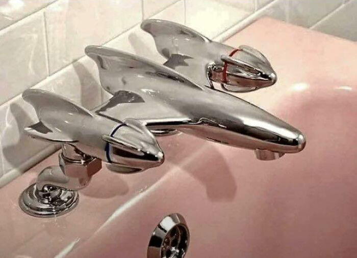 Chrome faucet shaped like vintage airplanes installed on a pink sink, a unique historical artifact from the museum of artifacts.