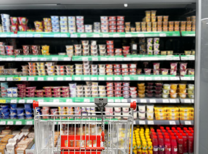 Shopping cart facing store shelves stocked with various food products illustrating brutal wake-up calls in everyday life.