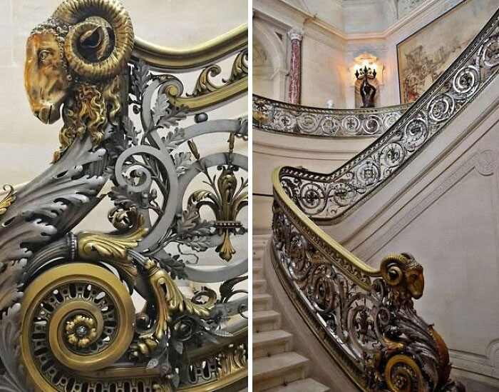 Ornate museum staircase railing featuring detailed ram head sculptures and intricate historical artifact design elements.