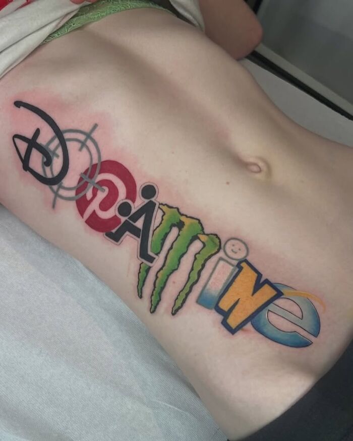 Colorful tattoo on side torso combining popular logos into the word gaming, showcasing a weirdly hilarious image.