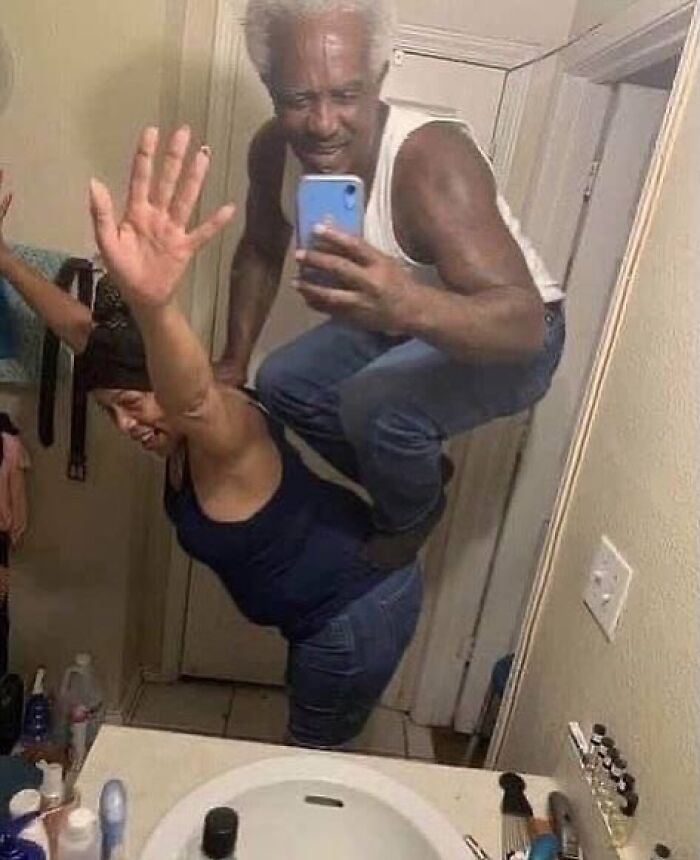 Two people striking a funny pose in a bathroom mirror selfie, capturing a weirdly hilarious moment for a fun feed.