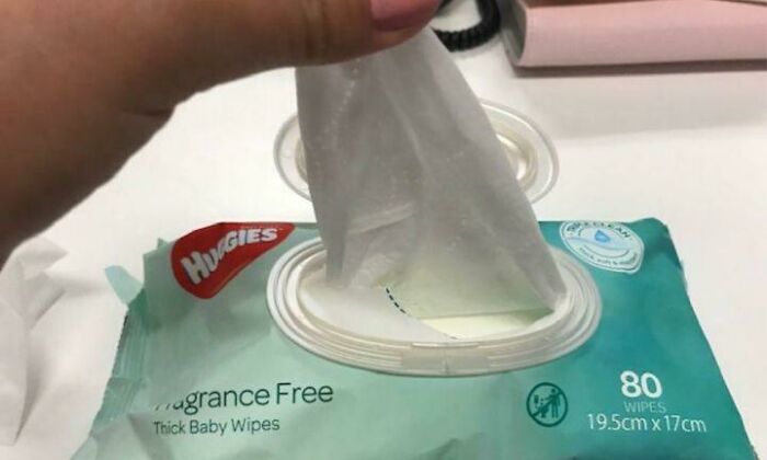 Hand pulling a baby wipe from a fragrance-free pack, illustrating a funny and harmless conspiracy theory concept.