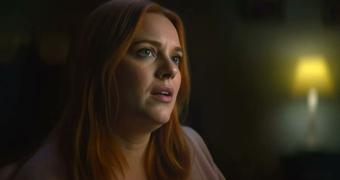 A woman with red hair appears emotional in a dimly lit room in the Netflix Lucy Letby documentary.
