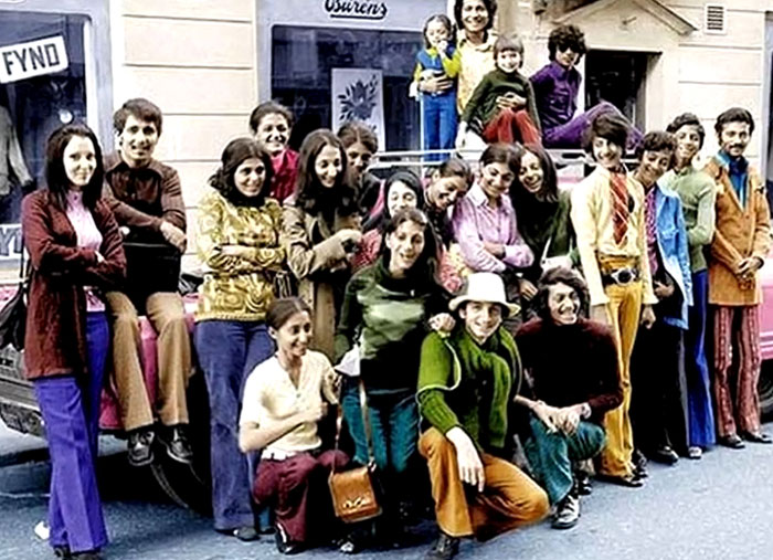 Group of people in colorful 1970s clothing posing on a city street, a rare and intriguing photo showing history.