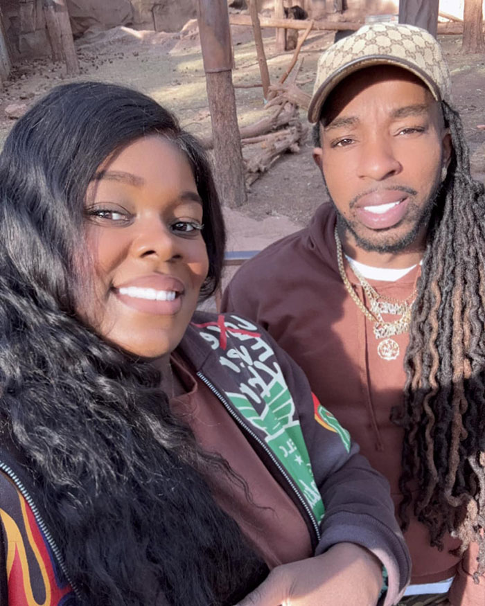Couple posing outdoors, smiling at the camera, related to surrogate suing couple after learning they had 21 kids.