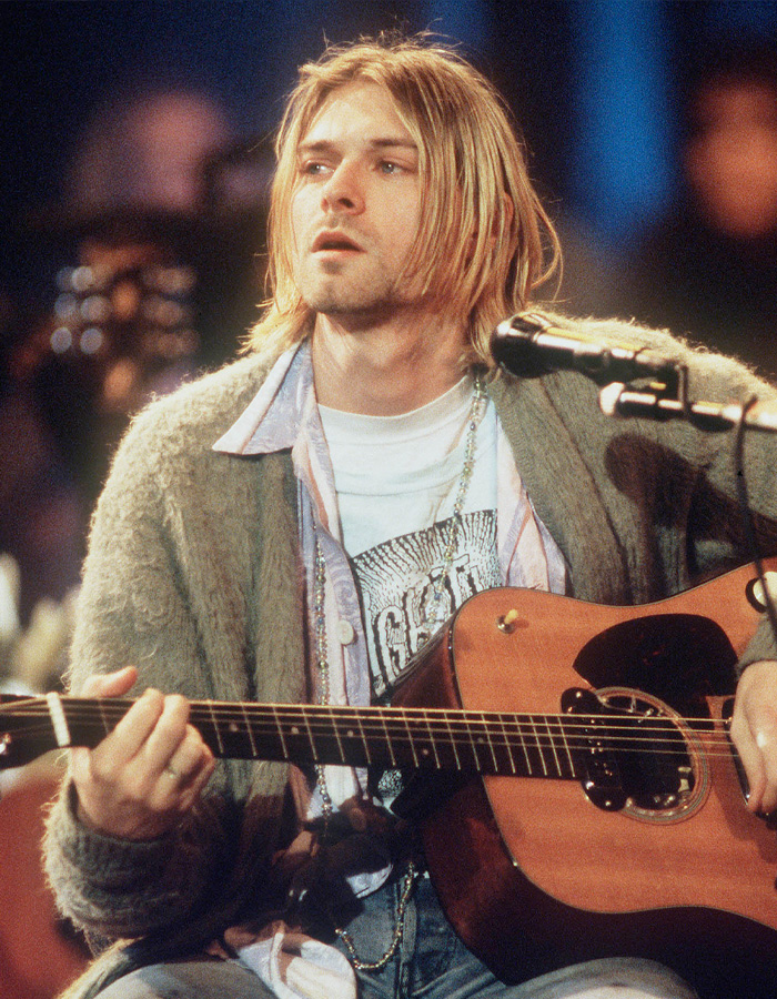 Kurt Cobain playing guitar during a live performance, related to Courtney Love's reaction to homicide claim report.
