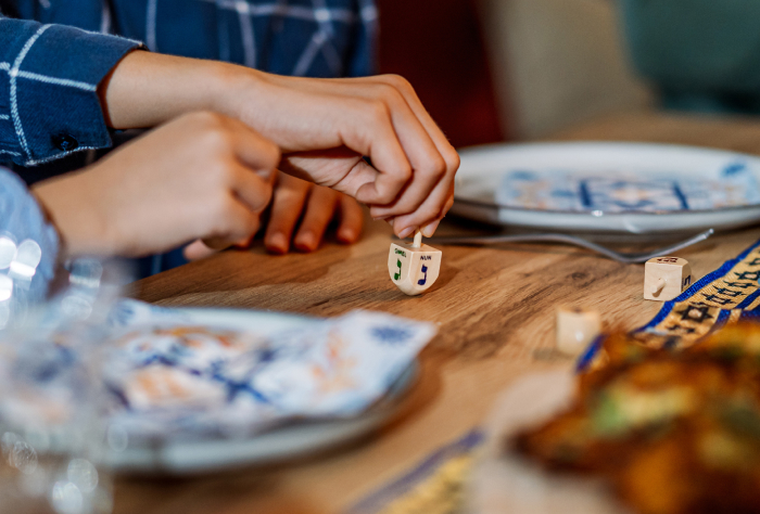 Hands spinning a Google dreidel on a wooden table during Hanukkah, highlighting a digital age holiday activity. Hands spinning a Google dreidel on a wooden table during Hanukkah, highlighting a digital age holiday activity.