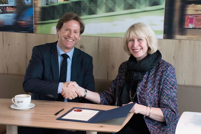 Two people shaking hands over a document, smiling during a friendly meeting with coffee on the table – today I learned facts