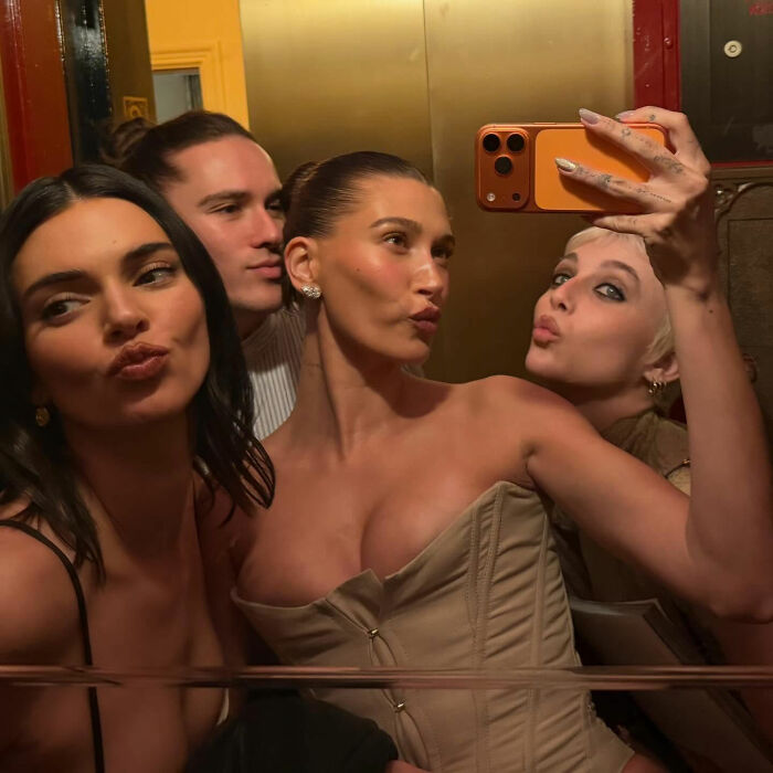 Group selfie of three women and one man posing and making kiss faces, linked to Justin Bieber Grammy controversy.