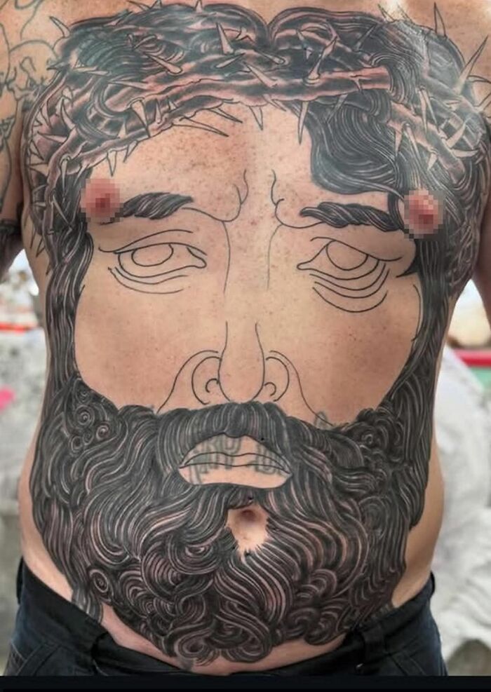 Large poorly done tattoo on a man's torso featuring an outlined face with a detailed beard and crown of thorns.