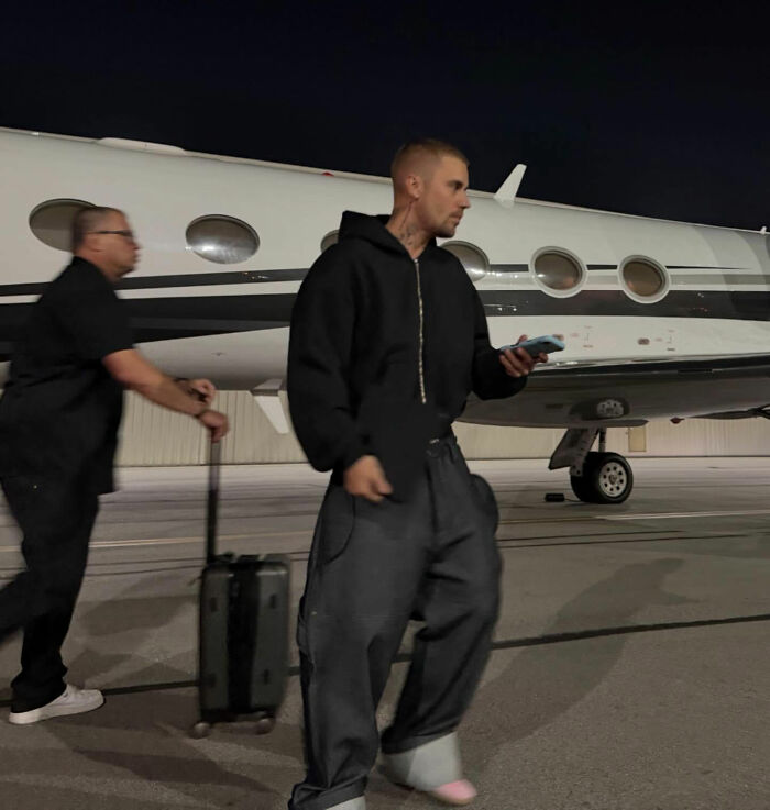 Justin Bieber walking near private jet at night showing fans cry foul after Grammys exit with another woman.
