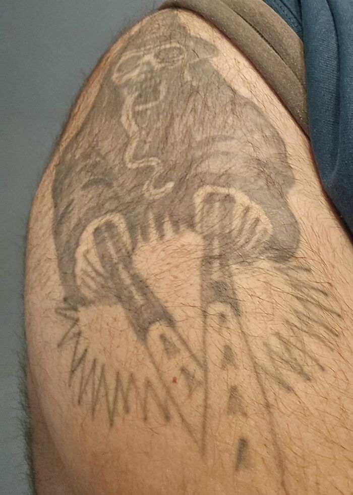 Poorly executed tattoo of an unclear animal on a hairy upper arm, illustrating bad tattoos and design mistakes.
