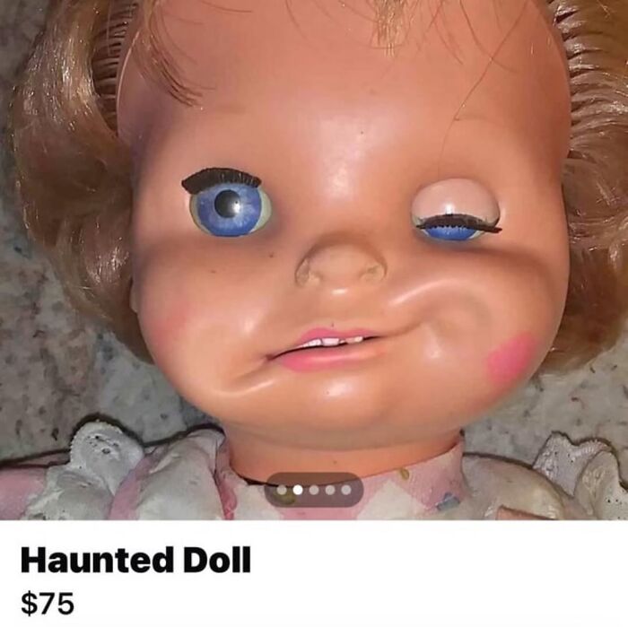 Close-up of a weirdly hilarious haunted doll with one eye open and a crooked smile for a funny feed boost.