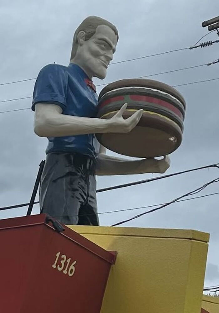 Giant roadside attraction of a man holding a large burger, showcasing quirky USA roadside attractions to see.