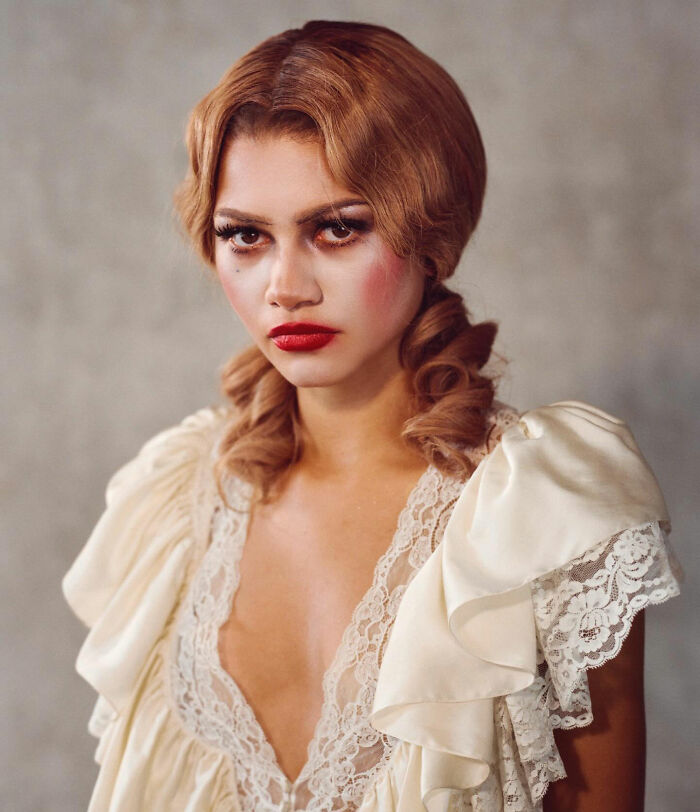 Woman with vintage hairstyle and bold makeup wearing a lace-trimmed dress in a gender-bending photoshoot look.