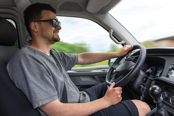 Man wearing sunglasses driving a car, representing wild dating experiences that made people question reality.