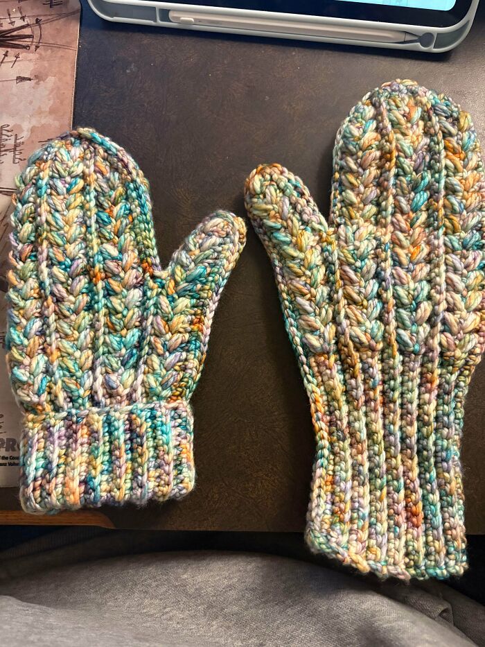 A pair of colorful crocheted mittens, one smaller than the other, showcasing awesome crochet skills.