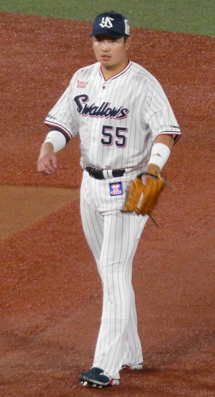 Munetaka Murakami wearing a Swallows uniform on a baseball field holding a glove during a game.