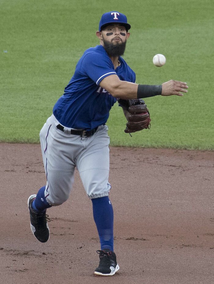 Rougned Odor in Texas Rangers uniform throwing a baseball during a game on the field.