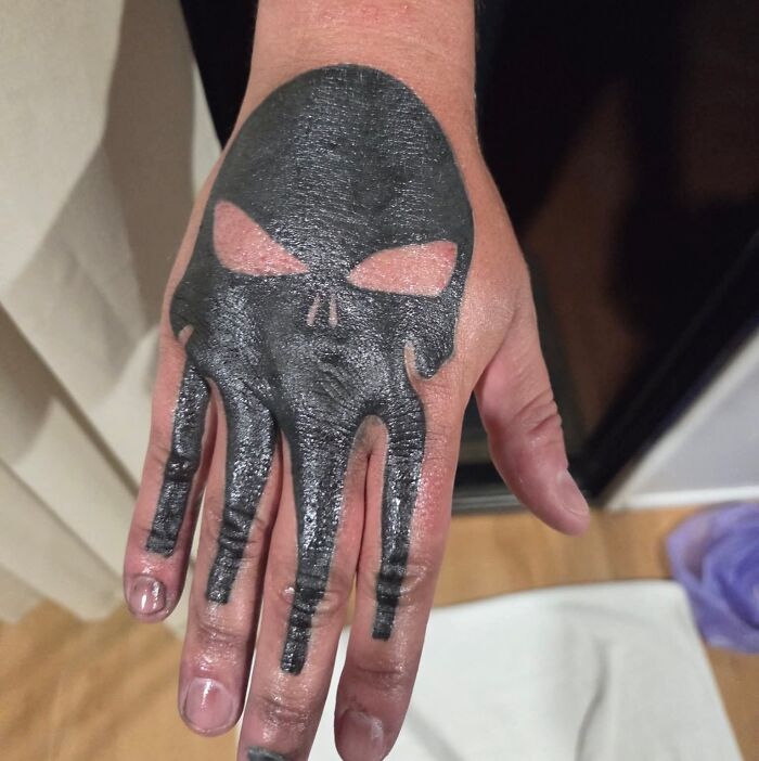 Hand tattoo with a black skull design extending onto fingers, an example of bad tattoos that prove thinking first is optional.