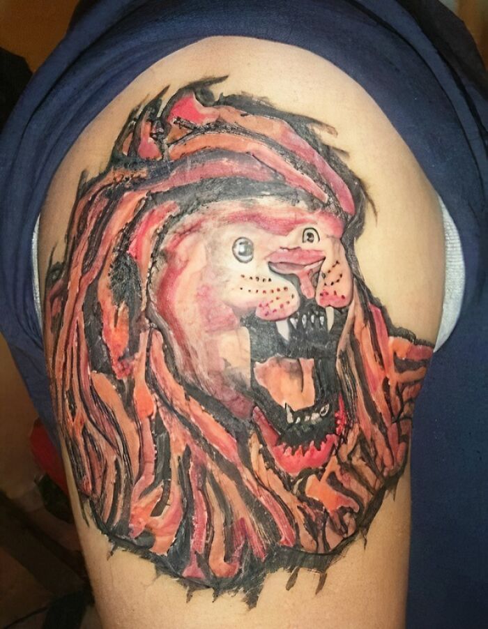 Close-up of a poorly executed lion tattoo on upper arm showing bad tattoos that prove thinking first is optional.