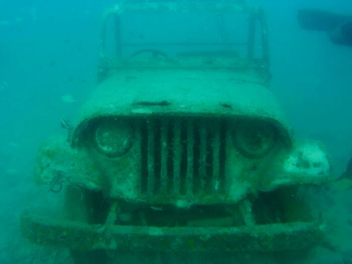 Underwater photo of an old rusted jeep covered in marine growth, an unexpected ocean scene that might freak you out.
