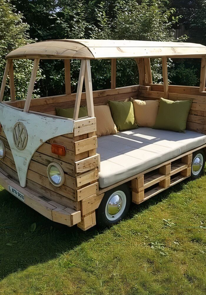 Woodworkers crafted a detailed wooden outdoor sofa shaped like a vintage van with cushions and realistic accents.