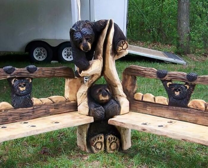 Woodworkers carved detailed bear sculptures into wooden benches, showcasing talented craftsmanship in outdoor furniture design.
