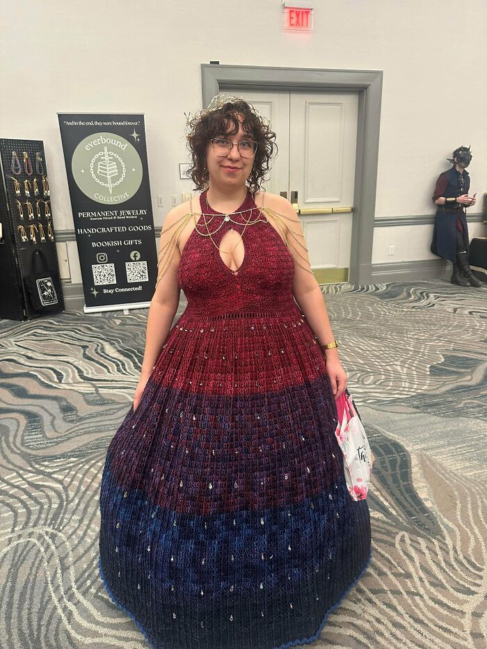 A woman in a beautiful crocheted dress, red to blue ombre with embellishments. This awesome crochet wowed the internet.