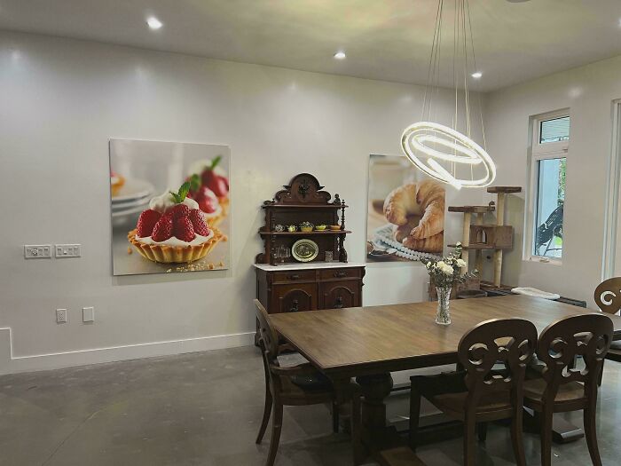 Modern dining room with wooden table and chairs, featuring ridiculous home decor and DIY wall art with food themes.