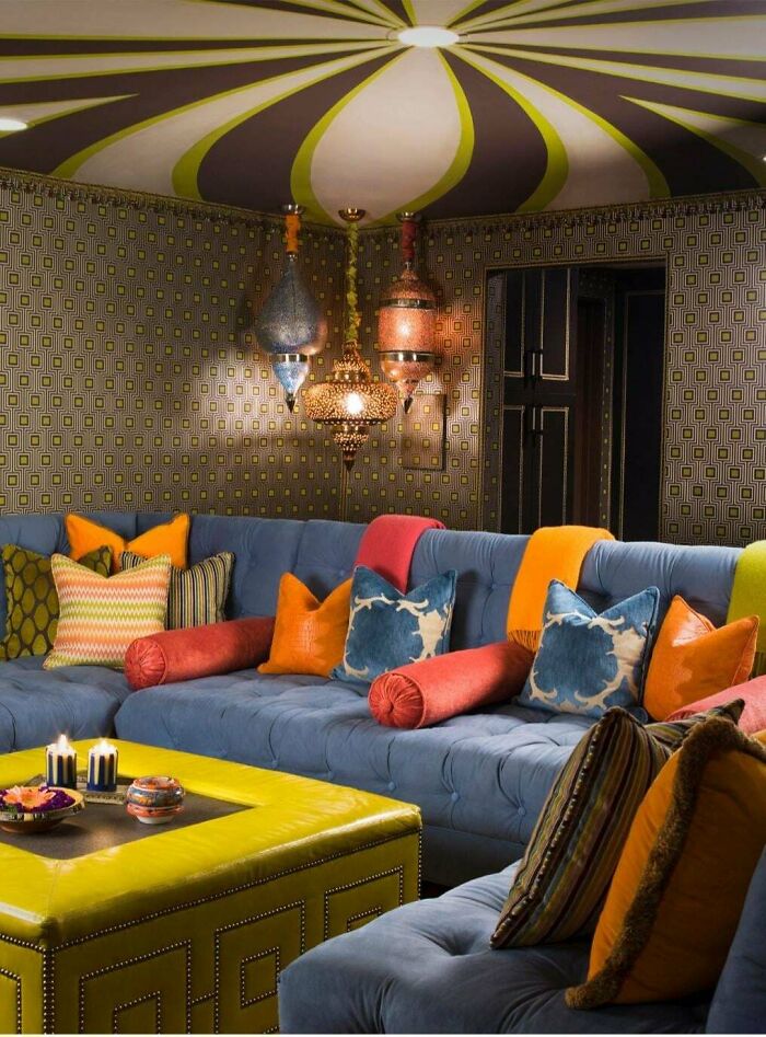 Colorful living room with bold home decor, patterned walls, and eclectic DIY style featuring various pillows and hanging lights.