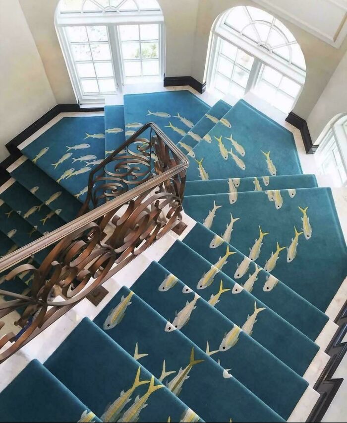 Blue stair carpet with a fish pattern creating an optical illusion of swimming fish in ridiculous home decor design.