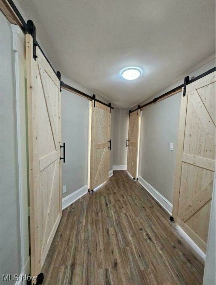 Hallway with four sliding wooden barn doors and wood flooring, showcasing unusual home decor and DIY design ideas.