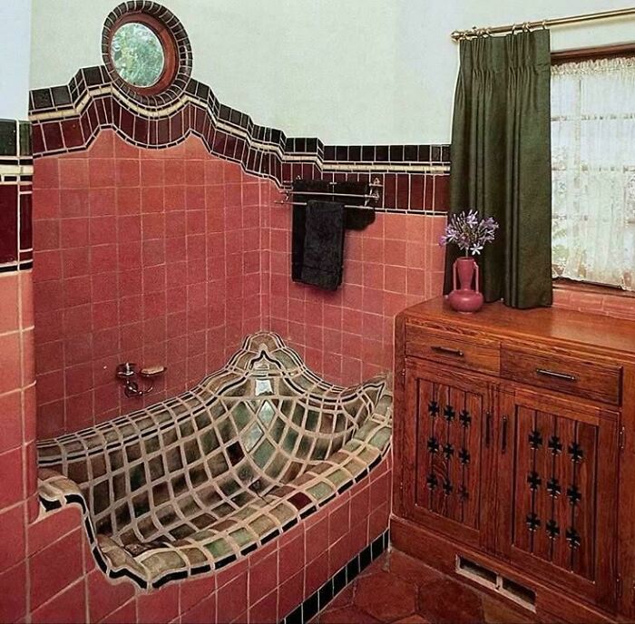 Ridiculous home decor featuring a tiled bathtub with an unusual design and wooden cabinet in a vintage bathroom setting.