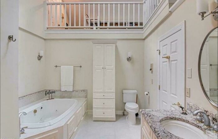 Bright bathroom with a large bathtub, white cabinetry, and marble countertop showcasing ridiculous home decor and DIY fails.