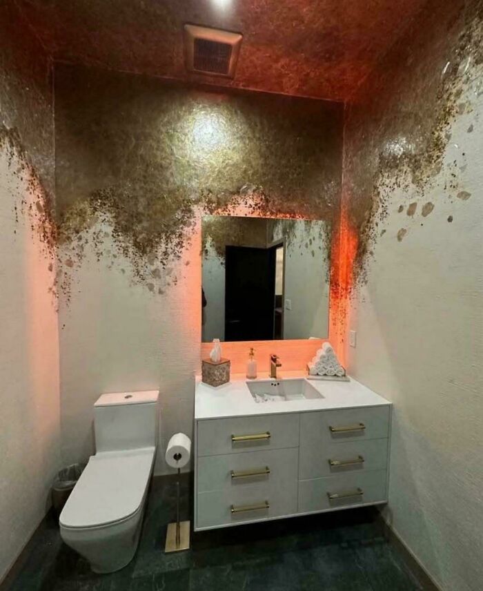 Bathroom with white toilet and sink vanity, walls decorated with unusual gold and brown textured home decor design.