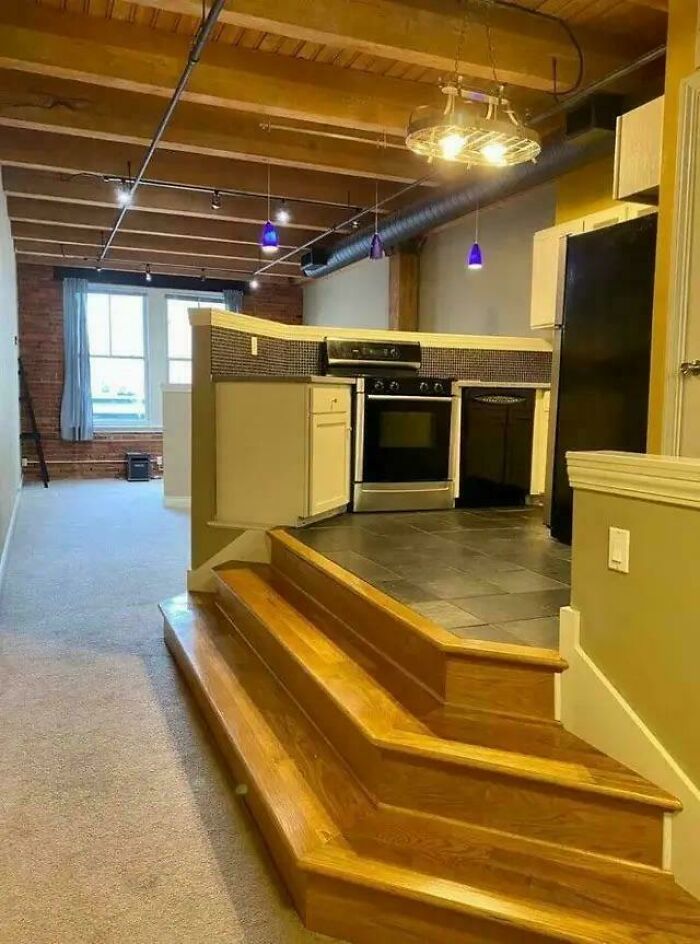 Kitchen with raised tiled floor and uneven wooden steps leading up, showcasing ridiculous home decor and DIY design choices.