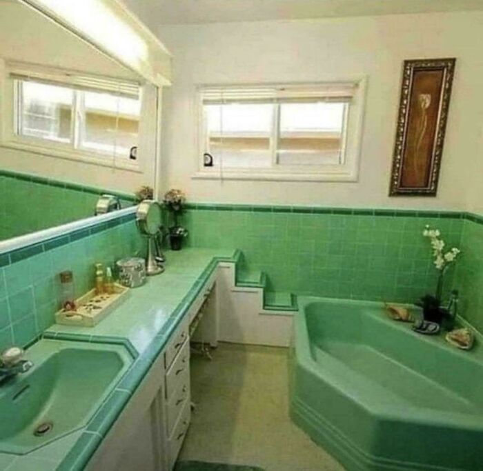 Bathroom with mismatched green tiled sink and bathtub, featuring a small staircase in the vanity area, showcasing ridiculous home decor.