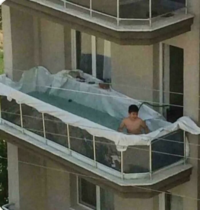 Child sitting in a makeshift pool on a balcony, an example of ridiculous home decor and DIY creativity.